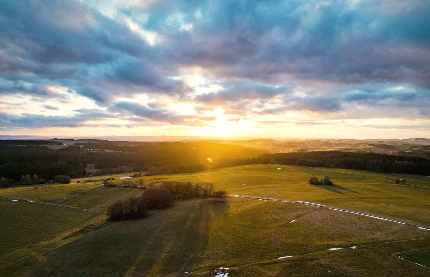 Solar array and wind turbines across open countryside at golden hour